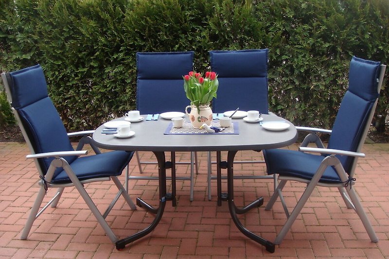 Große Terrasse mit Tisch, Stühlen und Blumenbeet. Perfekt zum Entspannen im Freien.