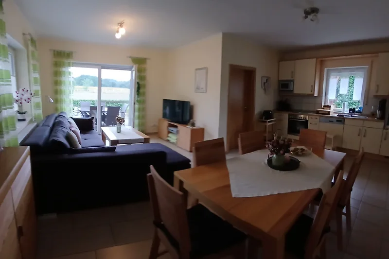Elegantes Wohnzimmer mit TV, Sofa und stilvollem Esstisch.