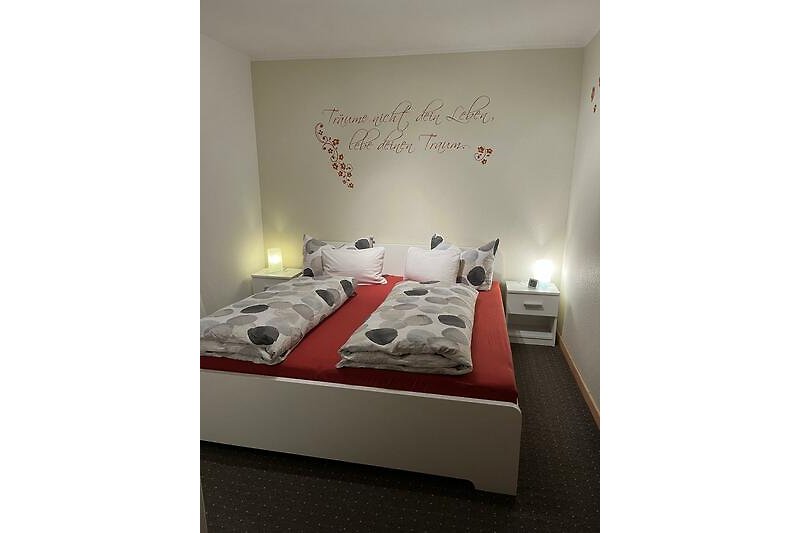 Schlafzimmer mit modernem Bett und stilvoller Kunst.