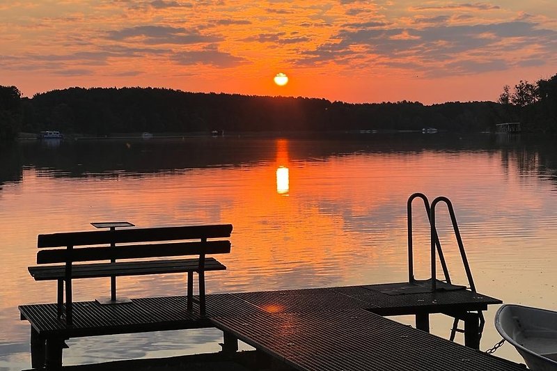 Ein ruhiger See bei Sonnenuntergang mit einem Holzsteg.