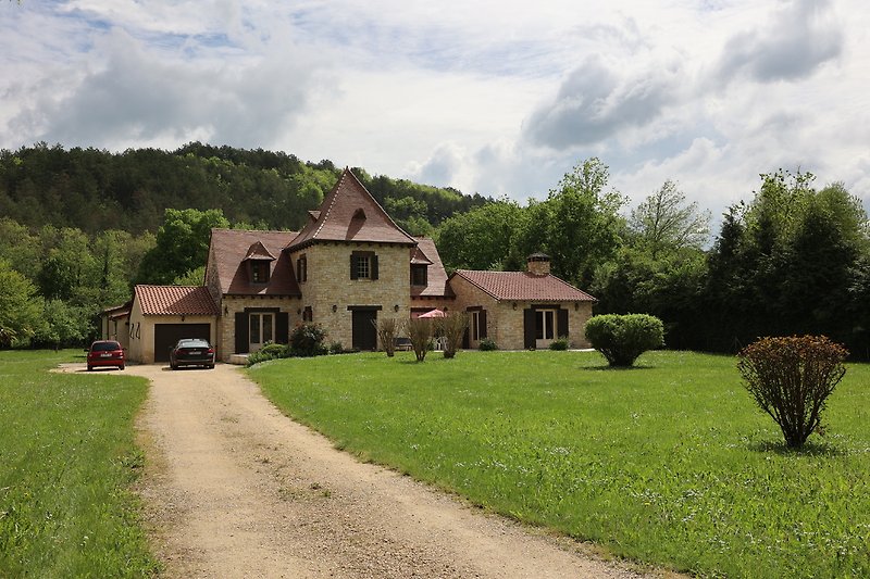 Une maison Périgourdine avec un jardin verdoyant et une belle façade.