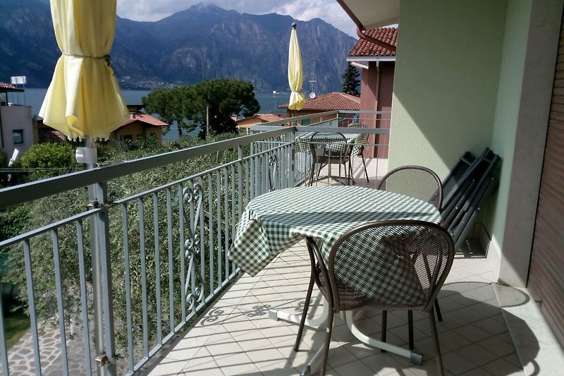 Balkon mit Tische/Stühle/Liegestühle, Sonnenschirm und Seeblick.