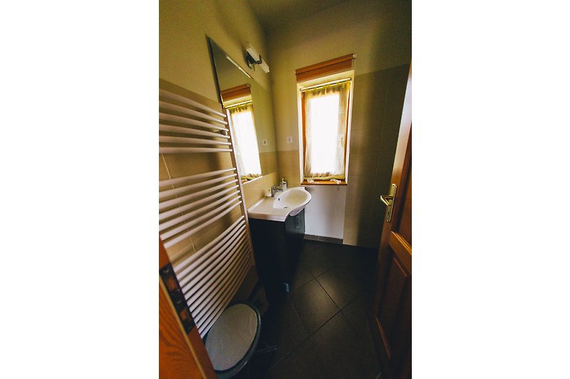 Gemütliches Badezimmer mit Fenster und Holzboden. Entspannen Sie sich in der Badewanne.