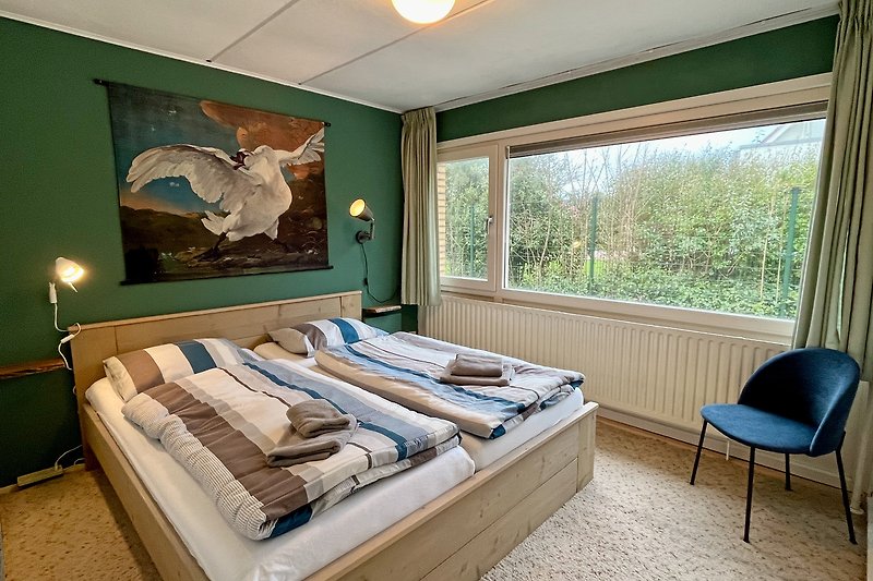 Stilvolles Schlafzimmer mit Holzbett und Kunst in der Ferienwohnung Wantveld in Noordwijk  am Meer