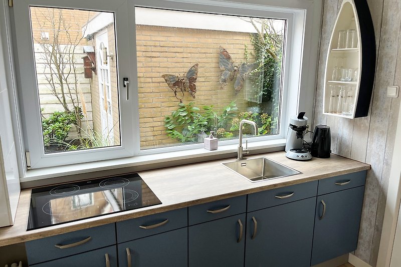Moderne Küche mit Holzschränken, Fenster und Arbeitsplatte.