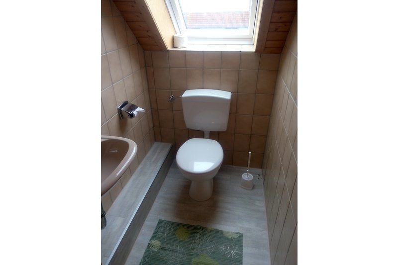 Toilette mit Holz-Toilettensitz und Keramik im Badezimmer.