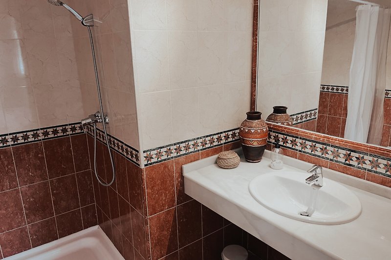 Ein stilvolles Badezimmer mit einer eleganten Spiegelwand und Marmorwaschbecken.