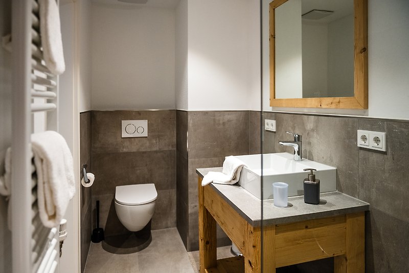 Ein modernes Badezimmer mit Spiegel, Waschbecken und stilvollen Armaturen.