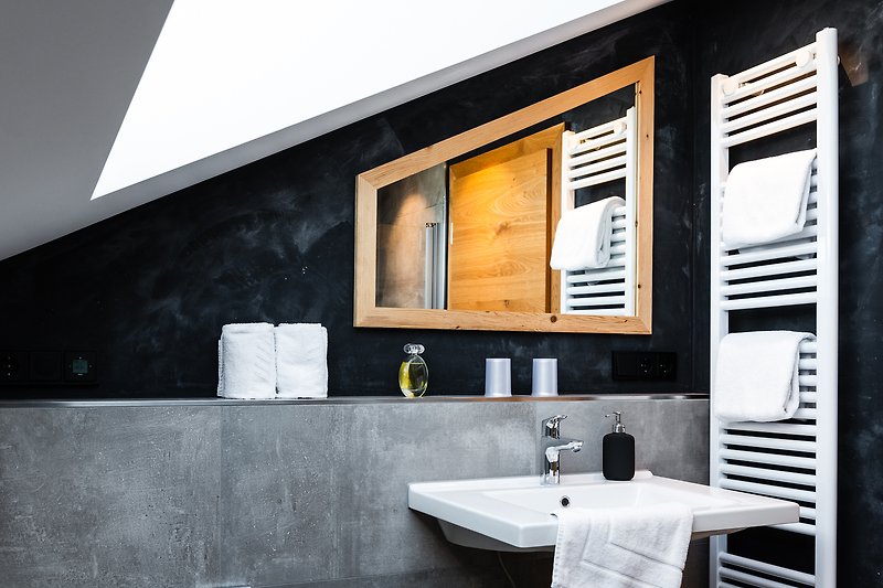 Schwarzer Spiegel über dem Waschbecken mit Holzschrank.