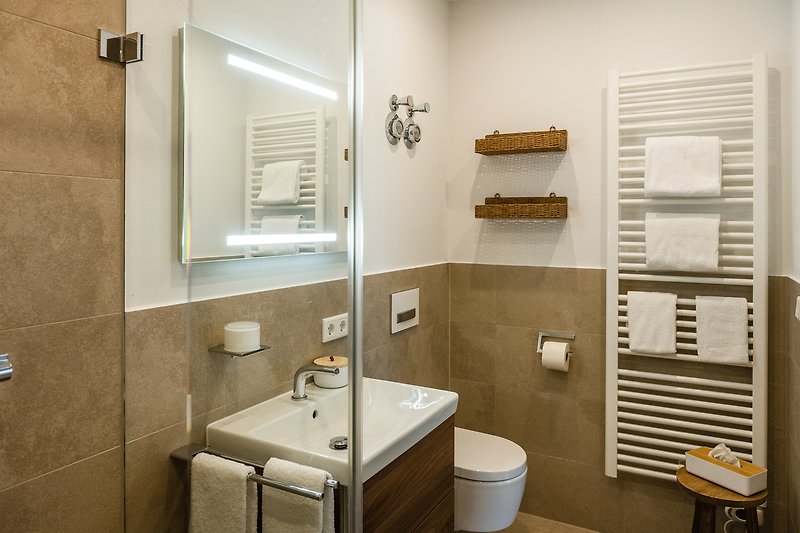 Moderne Badezimmerausstattung mit Spiegel, Waschbecken und Beleuchtung.