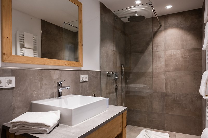Ein stilvolles Badezimmer mit Spiegel, braunem Waschbecken und modernen Armaturen.
