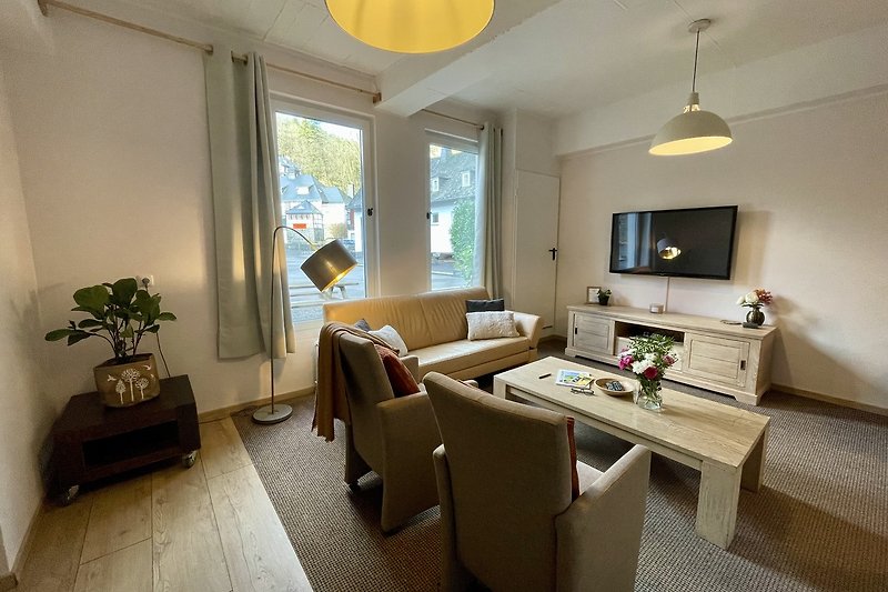Modernes Wohnzimmer mit bequemer Couch, stilvollem Tisch und gelber Beleuchtung.