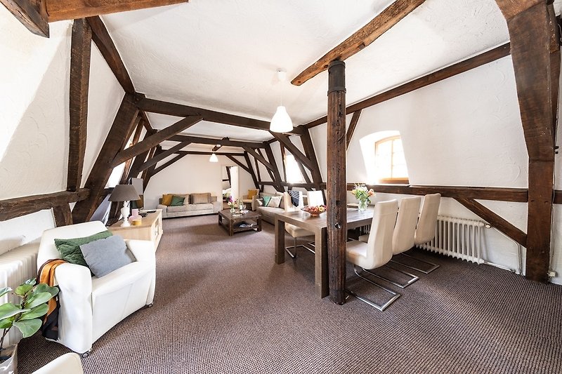 Stilvolles Wohnzimmer mit Holzbalken, Pflanzen und gemütlichen Kissen.