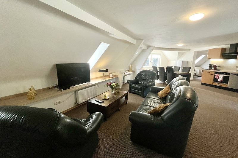 Modernes Wohnzimmer mit bequemer Couch, luxuriösem Fernseher und stilvoller Einrichtung.