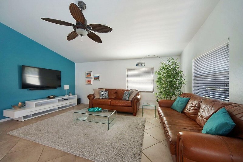 Gemütliches Wohnzimmer mit bequemer Couch, Pflanzen und Holzmöbeln.