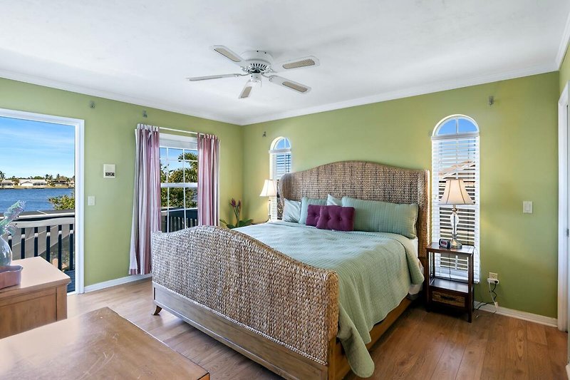 Schlafzimmer mit bequemem Bett, Kissen, Deckenventilator und Fenster.