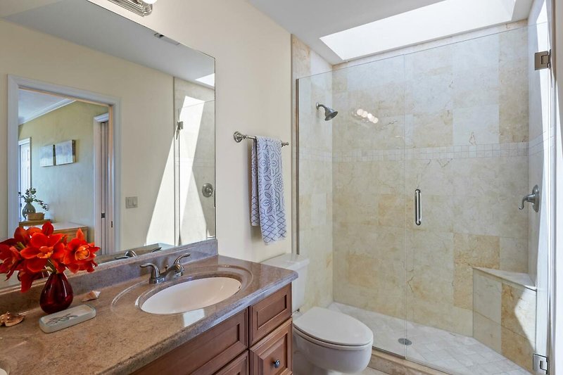 Modernes Badezimmer mit eleganten Holzmöbeln, Spiegel, Badewanne und Dusche.
