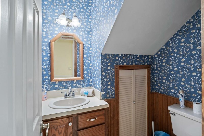Blaues Badezimmer mit Holzakzenten und Spiegel.