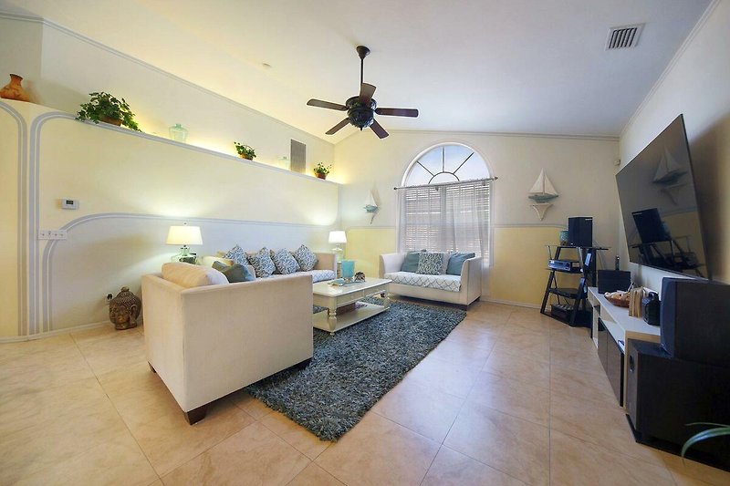 Schönes Wohnzimmer mit Holzboden, Deckenventilator und gemütlicher Couch.