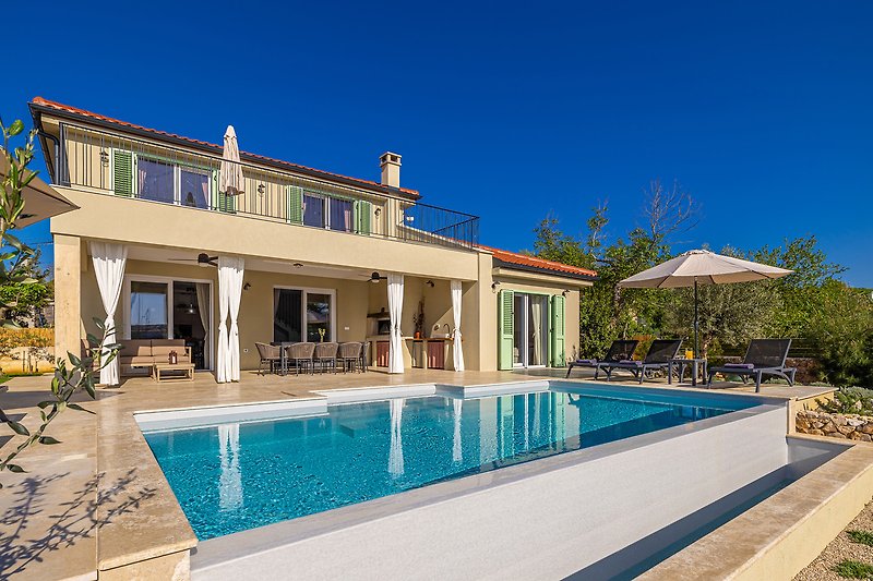 Luxuriöses Anwesen mit Pool, Palmen und Haus am Wasser.