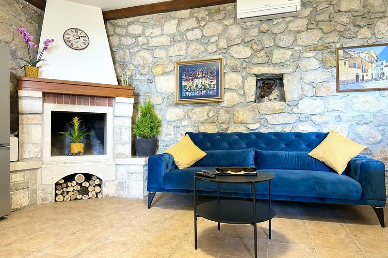 Wohnzimmer mit blauem Sofa, Holzboden und Pflanze.