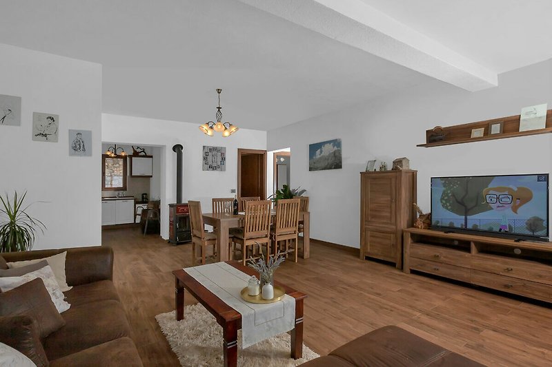 Gemütliches Wohnzimmer mit Pflanzen, Holzmöbeln und Kunst.