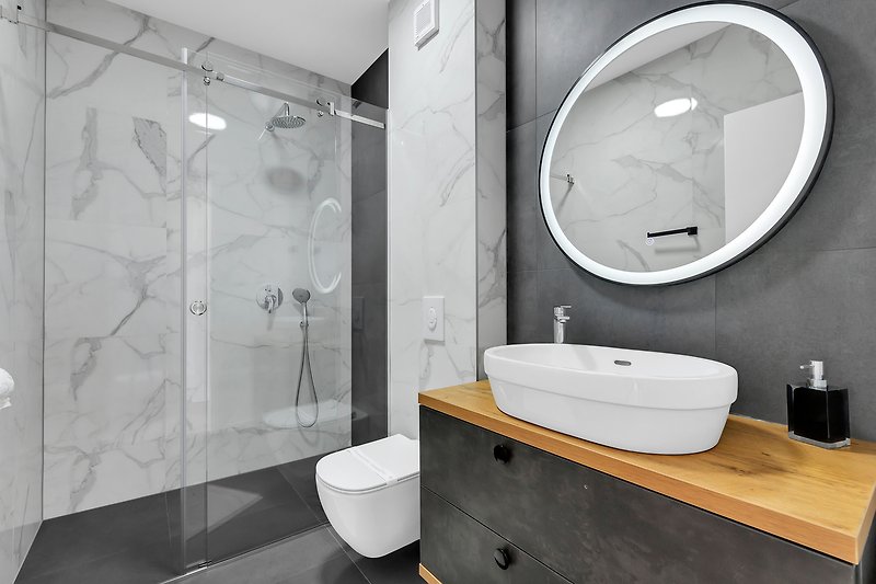 Stilvolles Badezimmer mit schwarzem Wasserhahn und weißem Waschbecken.
