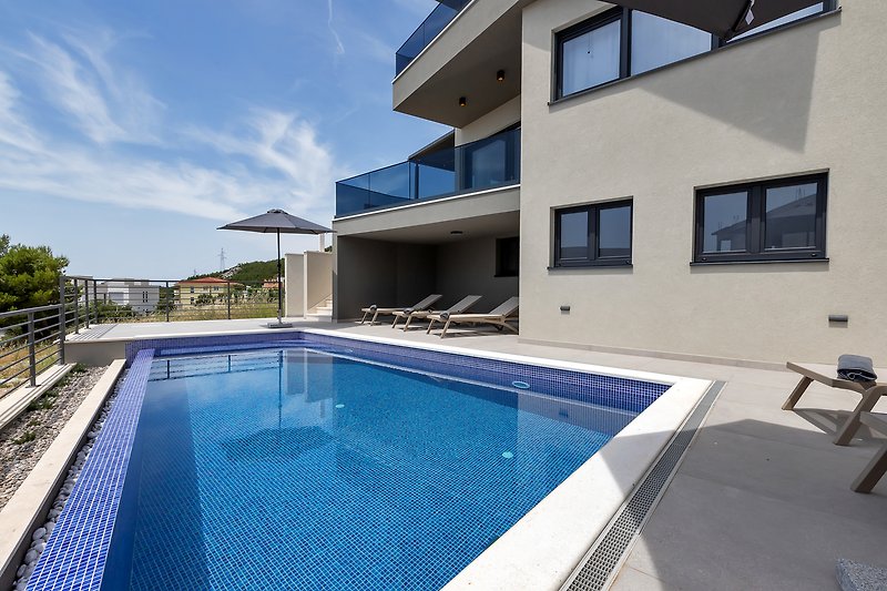 Schwimmbad mit modernem Design und stilvoller Außenmöblierung am Meer.