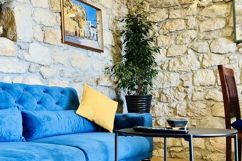 Wohnzimmer mit blauem Sofa, Holzboden und Pflanze. Gemütliche Einrichtung.
