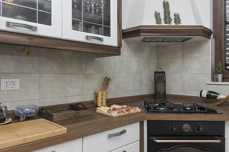 Gemütliche Küche mit Holzschränken, Gasherd und Fenster.