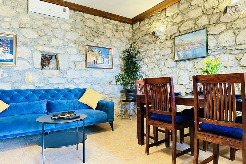 Wohnzimmer mit blauem Sofa, Holzboden und Pflanze.