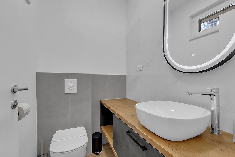 Ein stilvolles Badezimmer mit weißem Waschbecken und schwarzem Wasserhahn.