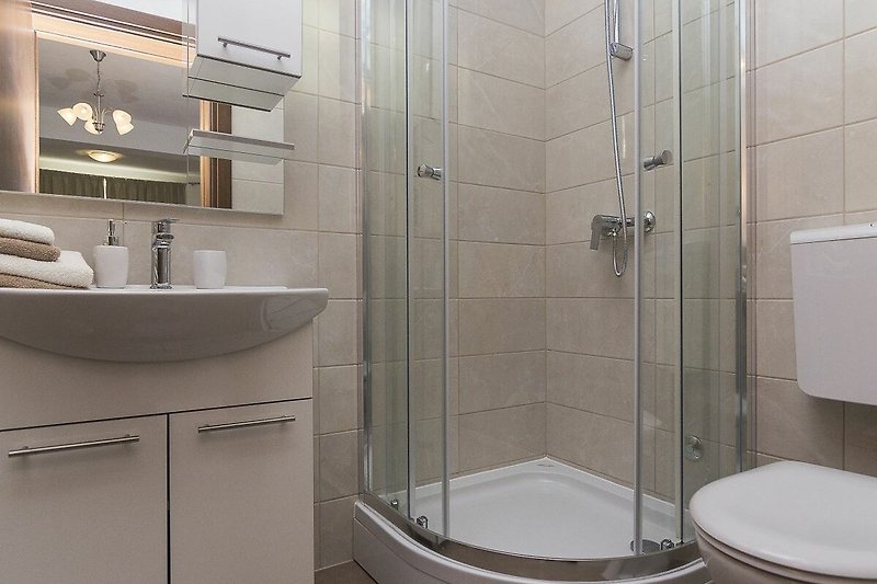 Modernes Badezimmer mit lila Akzenten, stilvoller Ausstattung und Glasdusche.