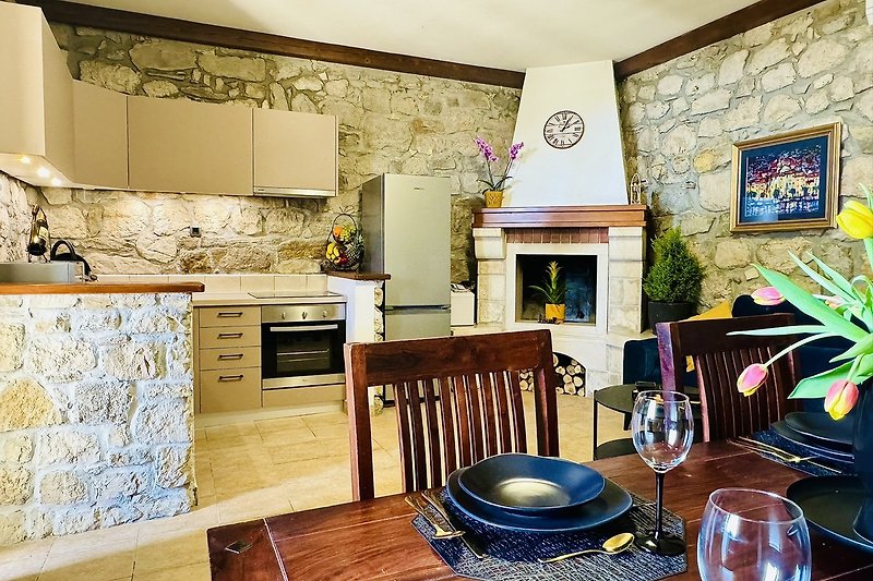 Küche mit Holzmöbeln, Geschirr und Uhr. Gemütlicher Essbereich.