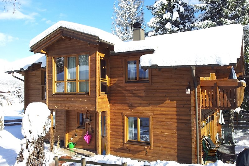 Gemütliche Holzhütte mit Schnee, Fenster und idyllischer Landschaft. Perfekt für den Winterurlaub.