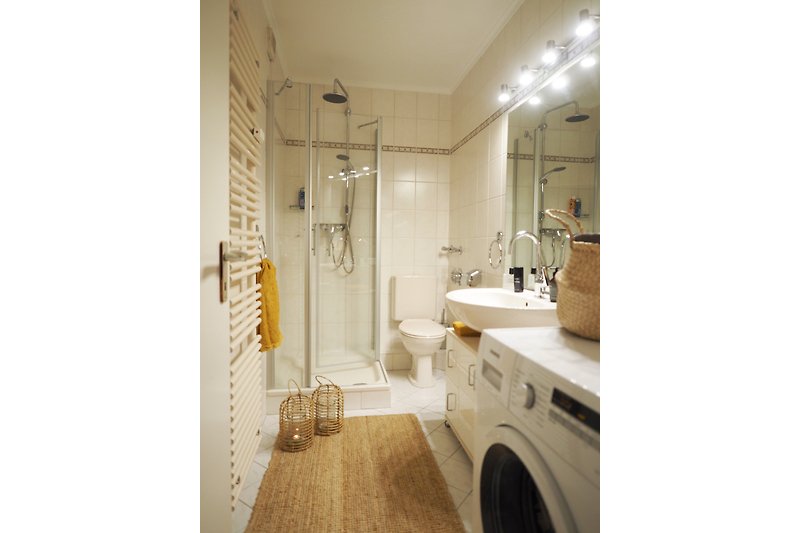 Modernes Badezimmer mit stilvoller Einrichtung, Wachmaschine und edlen Armaturen.