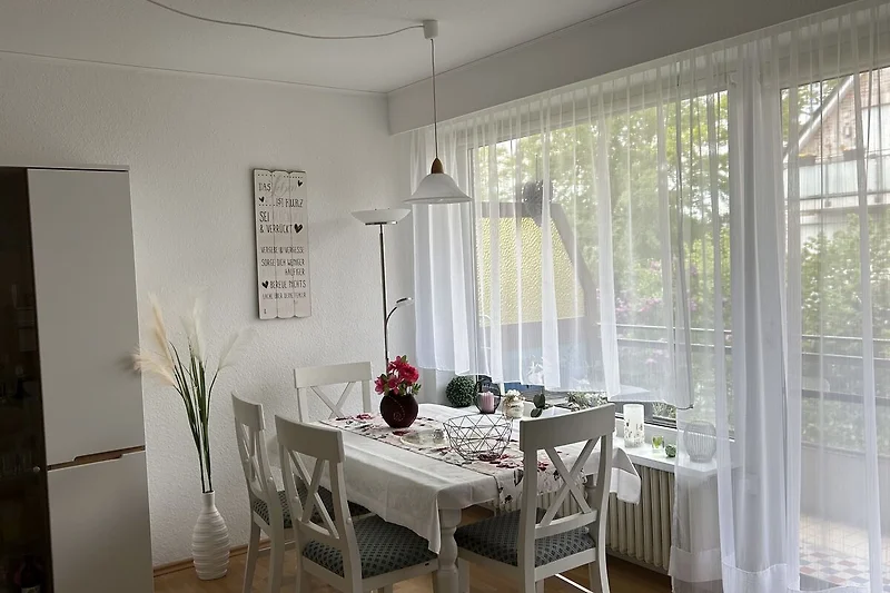 Großer Esstisch mit Glasvase, Lampen und eleganten Vorhängen.