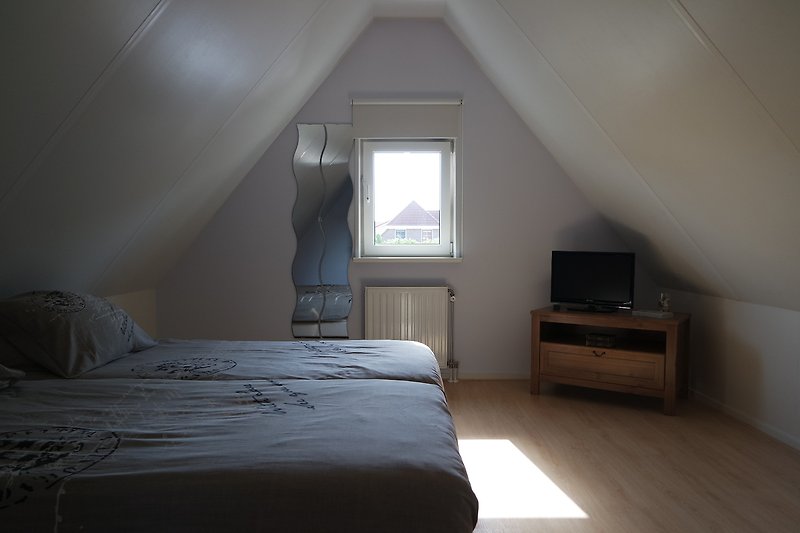 Schlafzimmer mit bequemem Bett, Fenster, Lampen und Vorhängen.