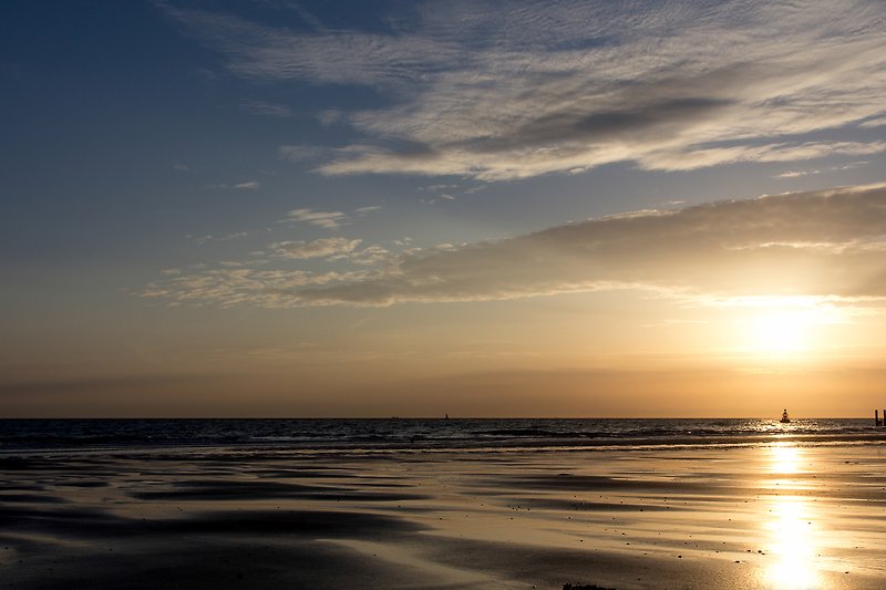 Strand mit ruhigem Wasser und Sonnenuntergang.