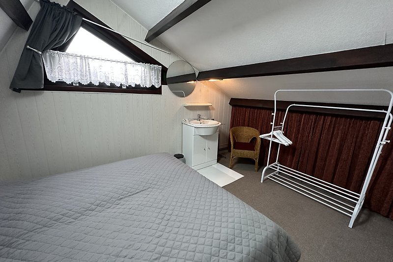 Schlafzimmer mit Holzbett, Vorhängen und Lampenschirm.