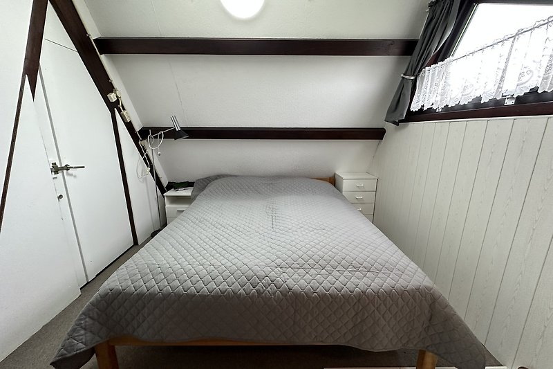 Schlafzimmer mit Holzbett, Metalltür und Kunst.