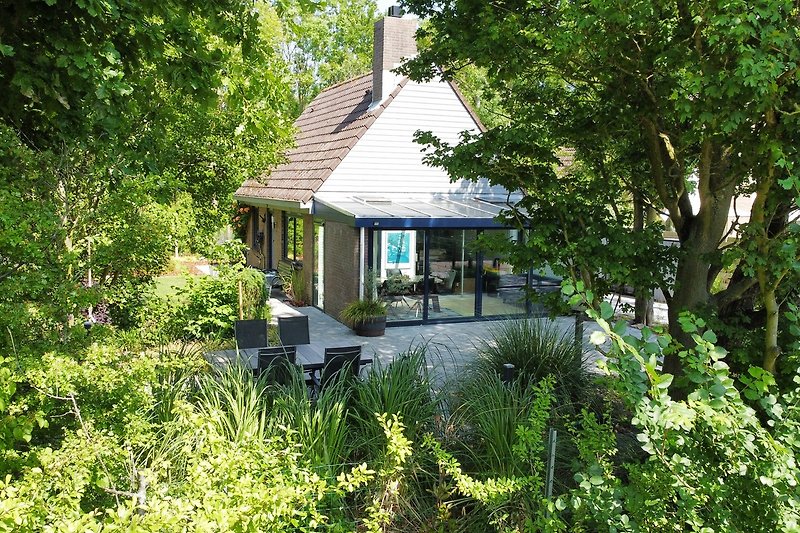 Garten mit Sträuchern und charmantem Landhaus.