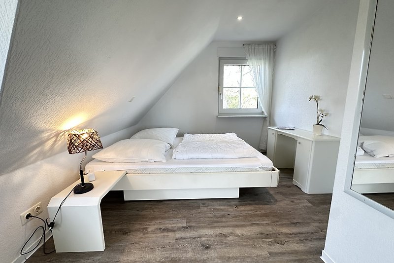Schlafzimmer mit Holzmöbeln, Bett und Nachttischlampe.