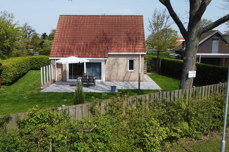 Traditionelles Haus mit Reetdach, Fenstern und Garten.