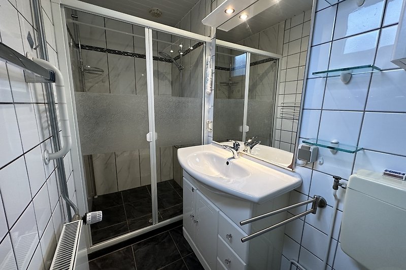 Modernes Badezimmer mit Glasdusche und Aluminiumarmaturen.