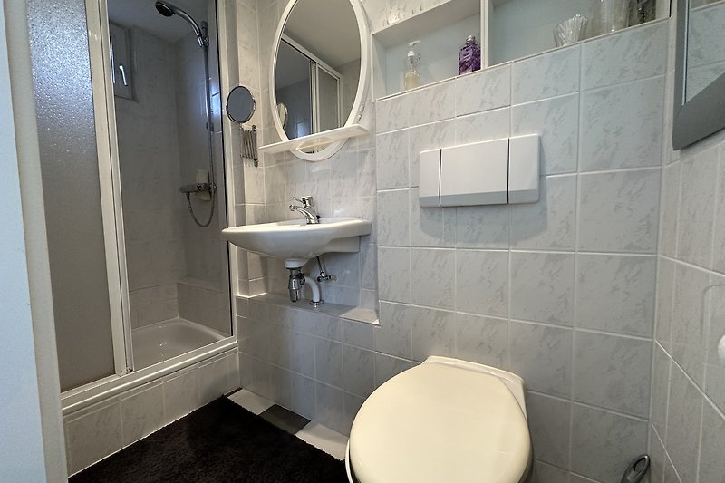 Badezimmer mit lila Akzenten, Toilette, Spiegel und Waschbecken.