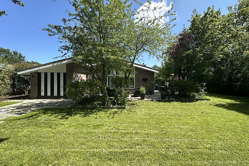 Bauernhaus mit Veranda, Garten und weitem Himmel.