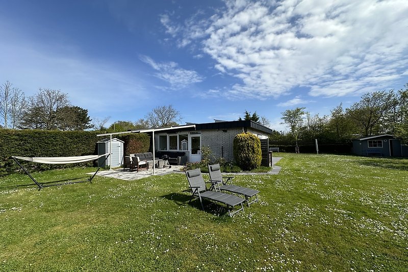 Ländliche Idylle mit Haus, Bank und Picknicktisch.