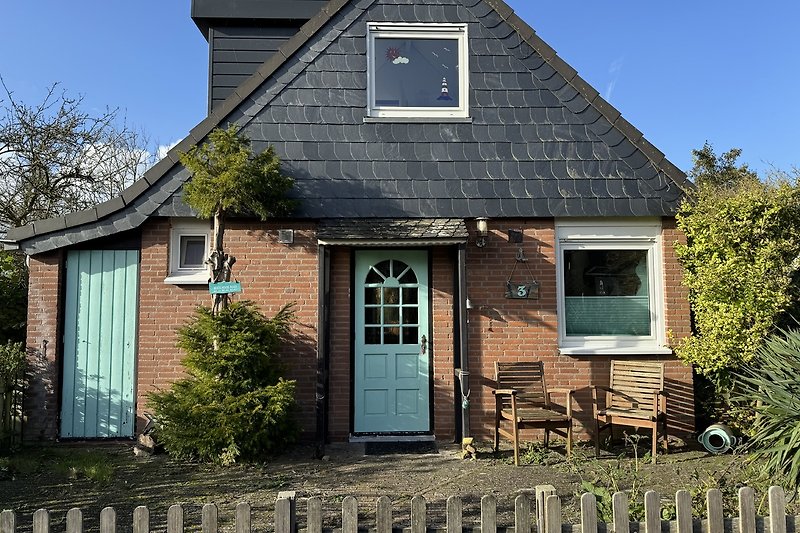 Historisches Haus mit Holzfassade, Fenstern und grünem Garten.