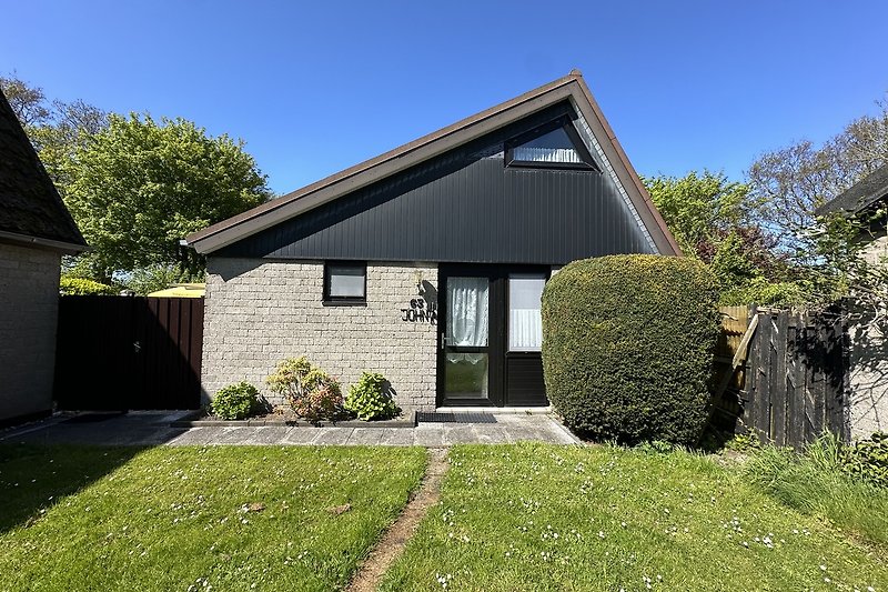 Ländliches Haus mit grünem Garten und blauem Himmel.